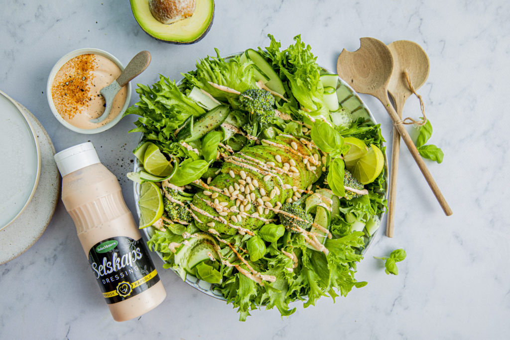Company dressing product on green avocado salad with broccoli